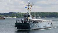 Ein graues Boot fährt über ein weitläufiges Gewässer