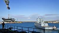 Ein graues Kriegsschiff auf offener Wasserfläche in einem Hafen