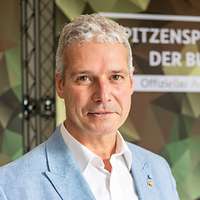 Porträt eines Mannes vor einer bunten Wand im Tarndruck 