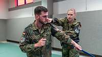 Eine Soldatin trainiert das Entwaffnen eines Messerangreifers in einer Sporthalle