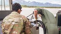 A US soldier assists a German soldier with refueling.