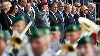 Mehrere Regierungsvertreter stehen nebeneinander auf der Tribüne beim Gelöbnis