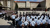 Soldaten marschieren in Formation auf dem Paradeplatz an angetretenen Soldaten vorbei