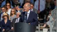 Bundeskanzler Olaf Scholz spricht am Rednerpult vor Publikum beim Gelöbnis