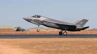 A fighter jet lands on an airfield.