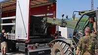 Der Gabelstapler Merlo verlädt einen Stromerzeuger in einen zivilen Lkw durch die Heckklappe