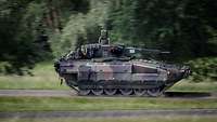 Ein Schützenpanzer in schneller Querfahrt auf einem Waldweg