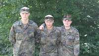 Drei Soldaten stehen Arm in Arm in der Natur