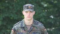Ein Soldat steht vor grünen Gewächsen