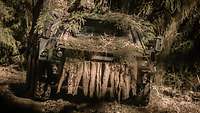 Ein getarnter Radpanzer im Wald. Ein Soldat blickt mit Gewehr in der Hand aus der Luke heraus.