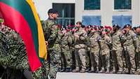 Mehrere Soldatinnen und Soldaten stehen in Formation. Vor der Formation steht ein weiterer Soldat