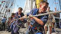 Marinesoldaten ziehen gemeinsam auf einem Schiff an einem Tau
