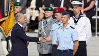 Bundeskanzler Scholz reicht einem Soldaten während eines Appells die Hand