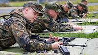 Mehrere Soldaten liegen auf dem Boden und zerlegen ein Gewehr G36