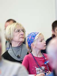 Ältere Dame sitz mit einem Kind auf dem Schoß in einer Veranstaltung