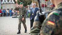 Feierliches Gelöbnis in Thüngen Ein Soldat und ein Zivilist im blauen Anzug schreiten gemeinsam eine Front von Soldaten ab.