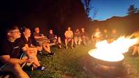 Die Teilnehmer der Rüstzeit sitzen um ein Lagerfeuer herum.
