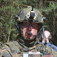 Ein Soldat mit Brille, Helm und Sprechsatz in der Sonne