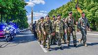 Mehrere Soldaten marschieren die Straße des 17. Juni entlang und werden von Feldjägern begleitet