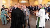 Beide Militärdekane geben Generaloberstabsarzt Dr. Ulrich Baumgärtner einen Wanderstab