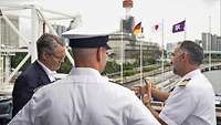 Zwei Marinesoldaten sprechen mit einem Mann in einem dunkelblauen Anzug