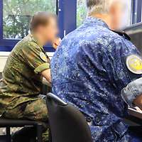 Deutsche und niederländischer Soldat Seite an Seite an ihren Computern.