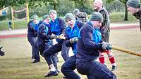 mehrere Soldaten in Sportanzug ziehen an einem Tau