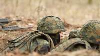 Ein Soldat mit Helm liegt im Graben.