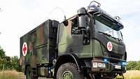 Ein Militär-Lkw mit rotem Kreuz steht im Gelände