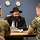 Ein Rabbiner mit schwarzem Hut unterhält sich an einem Tisch sitzend mit zwei Soldaten in Flecktarn