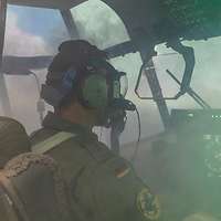 Ein Soldat mit Gasmaske sitzt in einem Cockpit voller Rauch.