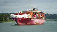 Ein beladenes Containerschiff fährt auf einem Gewässer