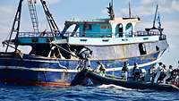 Soldaten legen mit einem Schlauchboot an einem Fischerboot an