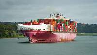 Ein beladenes Containerschiff fährt auf einem Gewässer