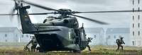 Aus einem Hubschrauber rennen mehrere Soldaten heraus, im Hintergrund Häuser.