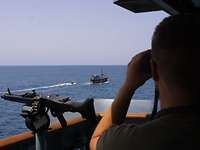 Ein Soldat beobachtet durch sein Fernglas ein Boot auf hoher See