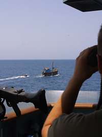 Ein Soldat beobachtet durch sein Fernglas ein Boot auf hoher See
