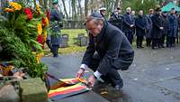 Boris Pistorius legt ein Blumenkranz an einer Gedenkstätte auf einem Friedhof nieder