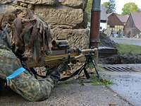 Ein Soldat liegt mit einem Gewehr im Anschlag an einer Häuserecke.