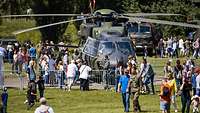 Soldaten und Besucher stehen am Hubschrauber NH-90 auf einem Gelände am Tag der Bundeswehr