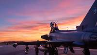 Ein Eurofighter steht auf dem Rollfeld und wird von drei Personen überprüft