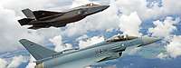 Zwei Kampfflugzeuge vom Typ F-35 und Eurofighter fliegen in Formation.