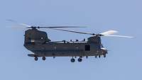 Ein Hubschrauber vom Typ CH-47 im Flug vor blauem Himmel.