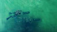 2 Soldaten schwimmen im Wasser mit Taucherflossen und einem motorisierten Antriebsgeräten