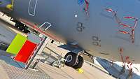 Eine aus dem Boden ragende elektrotechnische Einrichtung vor einem Transportflugzeug A400M.