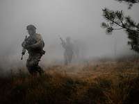 Auf einer Waldlichtung rennen vier Soldaten durch den dichten grauen Nebel.