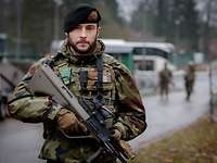 An einem Kasernentor mit Stacheldraht steht ein irischer Soldat mit Gewehr.