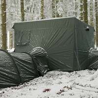 Miteinander verbundene Zelte stehen im verschneiten Wald