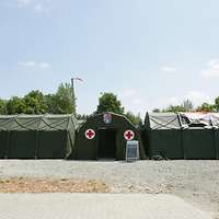 Ein Luftlanderettungszentrum steht auf Kiesuntergrund, mittig das Hauptzelt und seitlich abgehend je ein Nebenzelt.