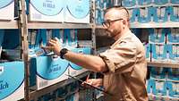 Ein Marinesoldat mit einer Milchpackung in der Hand im Lagerraum.